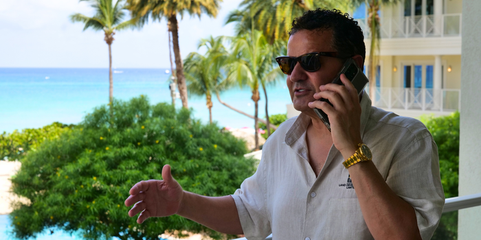A man taking a phone call on a balcony overlooking the sea on Grand Cayman