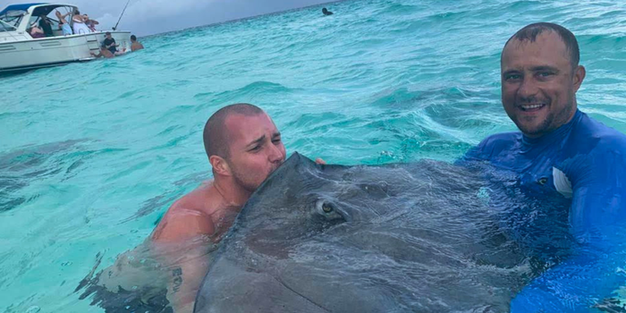 Two people in the water with a stingray at Stingray City, Grand Cayman