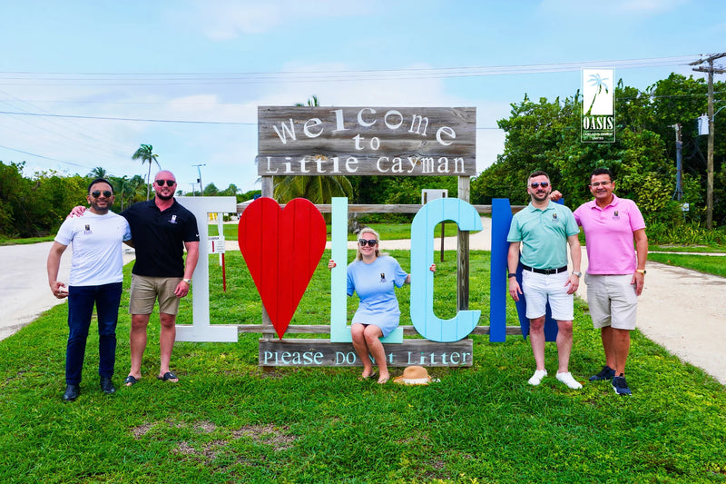 Oasis Land Development team at the 'I Love Little Cayman' sign, near available freehold land.